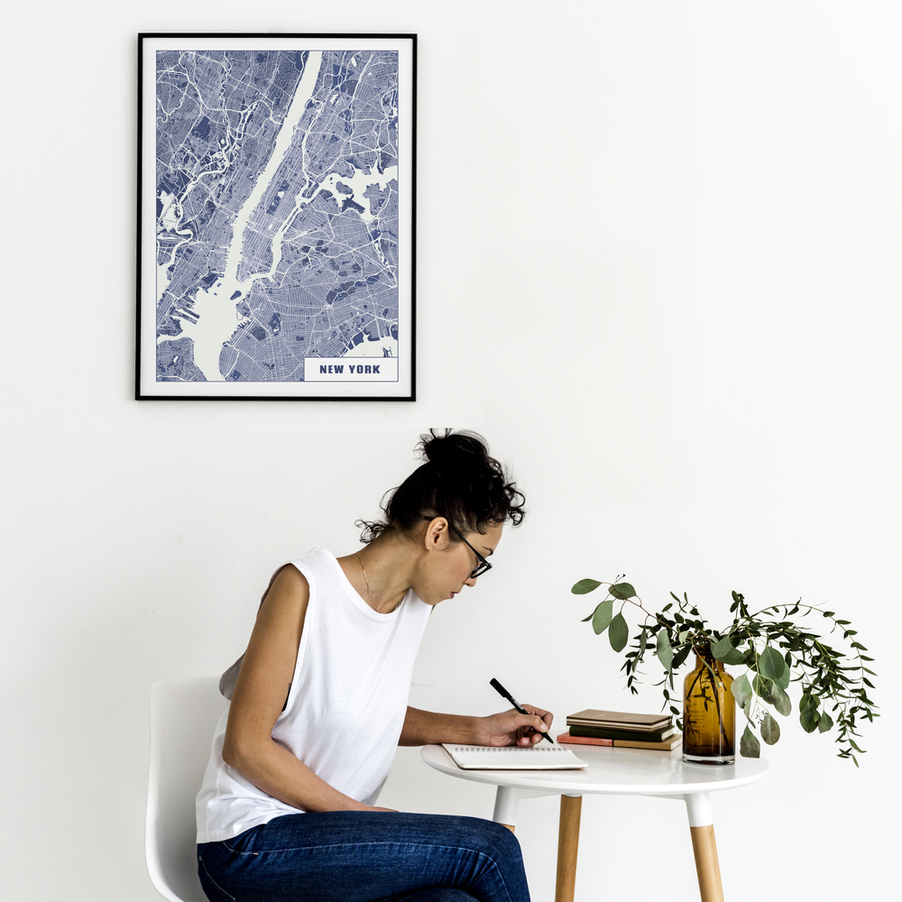 New-York-Stadtplanposter in Blau-Weiß mit schwarzem Rahmen an weißer Wand über einem kleinen Tisch