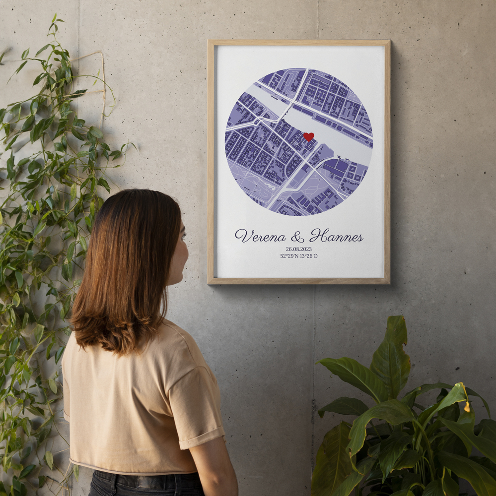 Geschenkidee zur Hochzeit: Stadtplan-Poster mit rotem Herz und Namen im hellen Holzrahmen an einer Betonwand